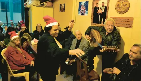  ?? BILAL HUSSEIN/AP ?? Amira Mansour, center, dances as Samir Damouni plays the oud during a community Christmas dinner Wednesday at Dbayeh refugee camp.