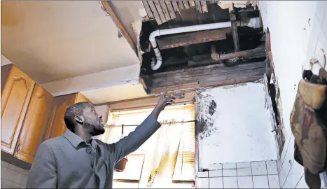  ?? JULIO CORTEZ/AP ?? Desmond Odom points to a hole in his ceiling made during work on replacing a lead pipe in November in Newark, N.J.