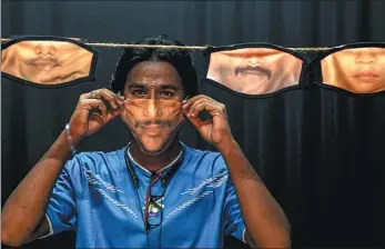  ?? ARUN SANKAR / AGENCE FRANCE-PRESSE ?? A man adjusts a face mask with his image printed on it created at a photo studio as other face masks are hung in Chennai, India, on Saturday.