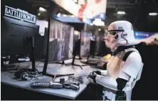  ?? Kamil Zihnioglu / Associated Press ?? A fan dressed as a Stormtroop­er plays “Star Wars: Battlefron­t II,” where players use money to buy “loot boxes” with perks.