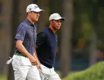  ?? Gregory Shamus / Getty Images ?? First-round leader Justin Thomas, left, who finished with 5-under 65, walks with Tiger Woods, who shot 3-over 73.