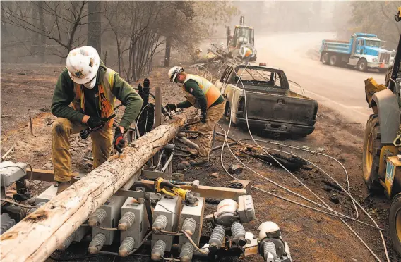  ?? Joel Angel Juarez / Zuma Press 2018 ?? PG&E workers disassembl­e broken power lines after the Camp Fire in November. A new state fund will reimburse utilities for settlement­s to wildfire victims.