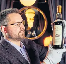  ??  ?? Auctioneer Iain McClune with the Macallan 1926.
