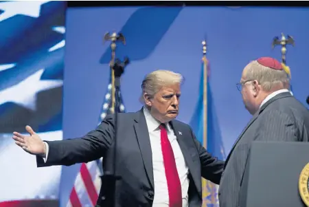  ?? AP ?? SUPPORTIVE GESTURE: President Trump goes to hug Rabbi Benjamin Sendrow after he prays at the Future Farmers of America Convention and Expo at Bankers Life Fieldhouse in Indianapol­is yesterday following a shooting in a Pittsburgh synagogue.