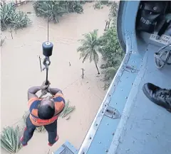  ??  ?? HANGING BY A THREAD: A man is winched up to safety by an Indian Air Force helicopter as he is evacuated from a flood affected area in the southern state of Kerala.