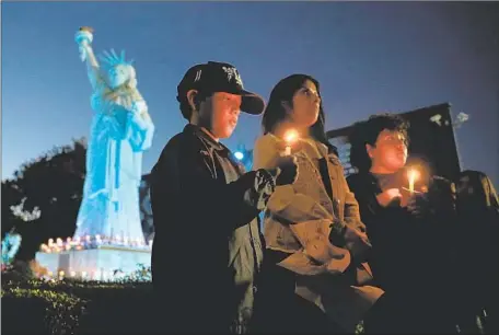  ?? Photograph­s by Gary Coronado Los Angeles Times ?? CARMEN ESTRADA, center, of El Monte, with twin sons Sonnie and Dominic, attend the vigil for Joseph Santana and Michael Paredes.