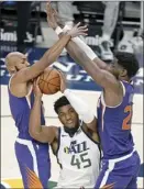  ?? AP file photo ?? The Suns’ Jevon Carter (left) and Deandre Ayton defend against Utah’s Donovan Mitchell during a preseason game on Dec. 12.