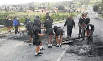  ?? Picture: SUPPLIED ?? FED UP WITH SITUATION: Breidbach High School pupils clear up the road into Breidbach after this week’s housing protest
