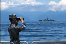  ?? THE ASSOCIATED PRESS ?? A Chinese soldier looks through binoculars during military exercises as Taiwan’s frigate Lan Yang is seen last week in this photo provided by China state media.