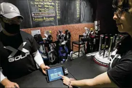  ?? NAM Y. HUH / ASSOCIATED PRESS ?? X-golf manager J.W. Park (left) helps Ashley Moreno check out at X-golf indoor golf in Glenview, Ill., last month. Tipping fatigue, it seems, is common in the U.S. as more businesses adopt digital payment methods that automatica­lly prompt customers to leave a gratuity.