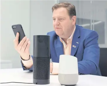  ?? AP ?? Gareth Gaston, executive vice president for omnichanne­l banking at U.S. Bank, discusses voice assistant banking with a mobile phone, an Amazon Echo, centre, and a Google Home, right, in New York.