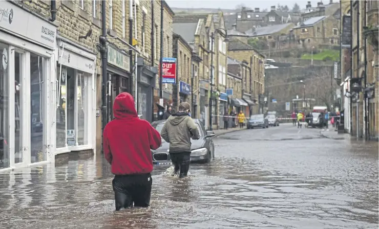  ?? ?? People wade through floodwater in the streets of Hebden Bridge, on February 9, 2020, as Storm Ciara swept over the country. Photo: Getty Images