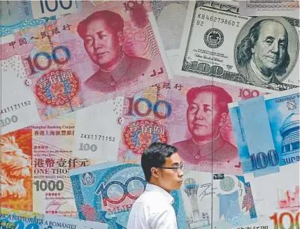  ?? Kin Cheung, The Associated Press ?? A man walks past a money exchange shop decorated with different banknotes at Central, a business district of Hong Kong. China's yuan fell below the politicall­y sensitive level of seven to the U.S. dollar on Monday.