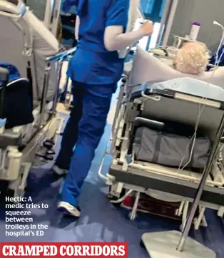  ?? ?? Hectic: A medic tries to squeeze between trolleys in the hospital’s ED
CRAMPED CORRIDORS