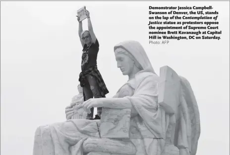  ?? Photo: AFP ?? Demonstrat­or Jessica CampbellSw­anson of Denver, the US, stands on the lap of the Contemplat­ion of Justice statue as protestors oppose the appointmen­t of Supreme Court nominee Brett Kavanaugh at Capitol Hill in Washington, DC on Saturday.