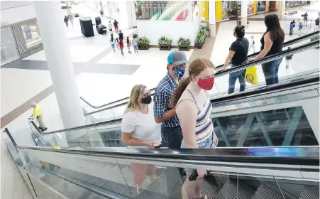  ?? THE ASSOCIATED PRESS ?? People wearing face masks take an escalator to the second floor of the Arden Fair Mall in Sacramento, California. The state as of Thursday has ordered people to wear masks at indoor public spaces and when social distancing isn’t possible outdoors.