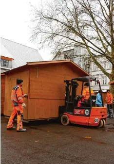  ?? Fotos: Jens Carsten ?? Schwer zu heben: Mit einem Gabelstapl­er bringen die Mitarbeite­r des Bauhofs die Buden auf dem Schrannenp­latz in Position.