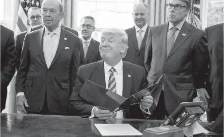  ??  ?? U.S. President Donald Trump, flanked by Commerce Secretary Wilbur Ross, left, and Energy Secretary Rick Perry, announces his approval of a permit to build the Keystone XL pipeline, Friday in the Oval Office at the White House.