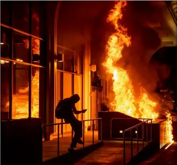  ?? AP Photo/Ethan Swope ?? Demonstrat­ors set fire to the front of the California Bank and Trust building during a protest against police brutality in Oakland, Calif., on Friday.