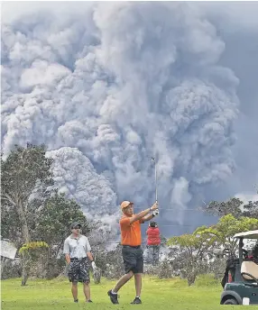  ?? MARIO TAMA/GETTY IMAGES ?? Golfers play in the shadow of an ash plume from the Kilauea volcano on Hawaii's Big Island on Tuesday.