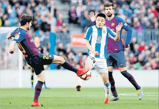  ?? ÀLEX GARCIA ?? Wu Lei, del Espanyol, pugna por el balón con Sergi Roberto, del Barça, con Piqué en segundo plano de la imagen