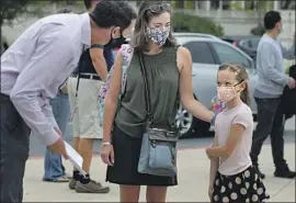  ?? Bill Wechter San Diego Union-Tribune ?? P R I N C I PA L Ryan Stanley, left, welcomes second-grader Maeva Chappaz, with mother Amelie Chappaz, as Ocean Air School in San Diego reopened on Sept. 8.