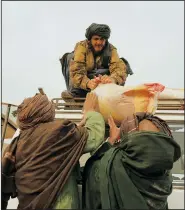  ?? ?? Afghan farmers load food rations on a truck in Sang-e-Atash.