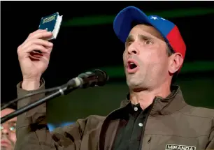  ?? AP ?? Henrique Capriles holds up a copy of constituti­on as he speaks to supporters during a meeting in Caracas, Venezuela. —
