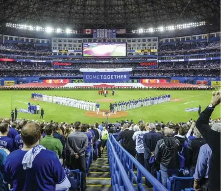  ?? DAVID COOPER/TORONTO STAR ?? A sold-out crowd at the Rogers Centre joins together to sing O Canada prior to Monday’s Blue Jays home opener against Tampa Bay.