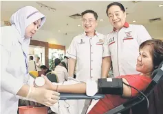  ??  ?? Wong (right) and Lo watching a medical staff attending to a blood donor.