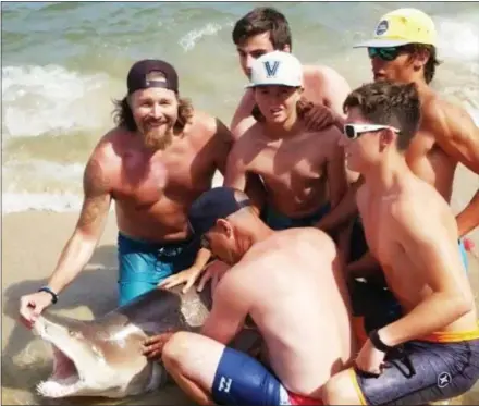  ?? SUBMITTED PHOTO ?? Aiden Hunsberger, in the Villanova hat, spent about an hour bringing in this 7-foot sand tiger shark June 30 at Beach Haven, N.J.