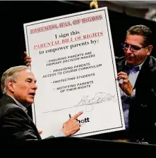  ?? Billy Calzada / Staff photograph­er ?? Gov. Greg Abbott signs a giant copy of his Parental Bill of Rights as state Rep. John Lujan, R-san Antonio, holds it for him during an appearance Monday at Picapica Plaza.