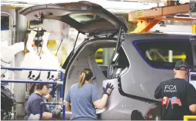  ?? NICK BRANCACCIO ?? Assembly line employees work on a Chrysler Pacifica in the Final Car area of FCA Windsor Assembly Plant last year.