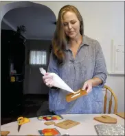  ?? TOM HAWLEY — THE MONROE NEWS VIA AP ?? Sandy Bergquist uses frosting with a cup of sugar as she starts to apply the frosting onto one of the sides of the gingerbrea­d house for the stain glass window made from melted hard candy at her home in Monroe.