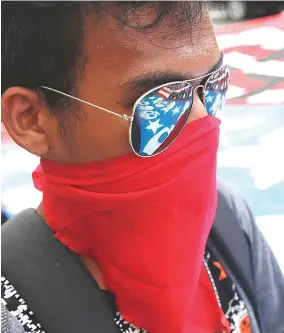  ??  ?? NO TO TRUMP VISIT – An anti-Trump protester beside a tarpaulin representa­tion of the American flag with skulls instead of stars. (Czar Dancel)