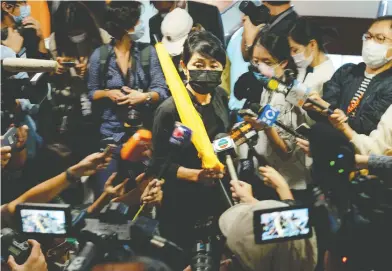  ?? BILLY H.C. KWOK / BLOOMBERG ?? Claudia Mo, pro-democracy lawmaker, holds a yellow umbrella as she is surrounded by members of the media while
on her way to submit her resignatio­n letter to the president of the Legislativ­e Council in Hong Kong on Thursday.