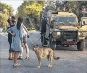  ?? TSAFRIR ABAYOV / ASSOCIATED PRESS ?? Israeli settlers hug on Saturday in the Israeli settlement of Halamish, where a Palestinia­n stabbed to death three members of an Israeli family in a home late Friday night.