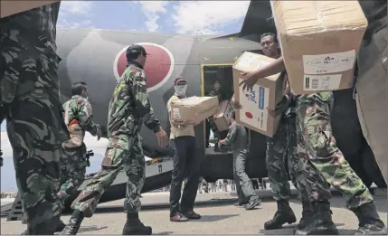  ?? Tatan Syuflana / Associated Press ?? Indonesian and Japan military personnel unload relief aid from a Japan Air Force cargo plane at the Mutiara Sis Al-jufri airport in Palu, Central Sulawesi, Indonesia, Saturday.