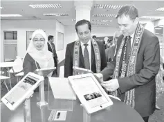  ??  ?? From left, Dayang Rukiah, Kamarudin and Hurst checking out the iPads provided at the American Corner.