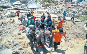  ?? RIFKI THE ASSOCIATED PRESS ?? A rescue team carries a victim after a major earthquake and tsunami in Palu, Indonesia. On Monday, a mass grave was being prepared in the hard-hit city as the death toll tops 840.