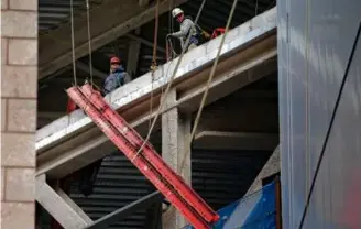  ?? JONATHAN WIGGS/GLOBE STAFF ?? Constructi­on employees worked to secure a beam Wednesday that fell from the South Station Tower constructi­on site.