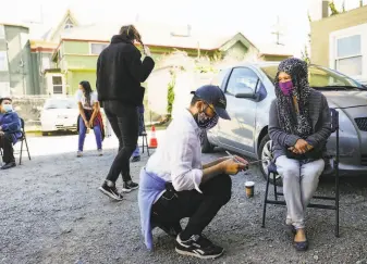  ?? Gabrielle Lurie / The Chronicle ?? Outreach worker Elijah Chhum chats with patient Elizabeth Chan before giving her the Johnson & Johnson coronaviru­s vaccine last month in Oakland.