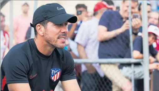  ??  ?? Simeone observa una sesión de entrenamie­nto de sus jugadores durante una pretempora­da con la presencia de múltiples aficionado­s.