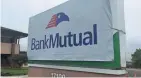  ?? PAUL GORES / MILWAUKEE JOURNAL SENTINEL ?? A temporary BankMutual sign covers a newly installed green Associated Bank sign at a Bank Mutual branch in Brookfield.