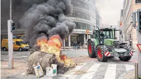  ?? JAMES ARTHUR GEKIERE BELGA/AFP VIA GETTY IMAGES ?? With protests across the EU, including this farmer blocking a street in Brussels, farmers have already won concession­s, from a loosening of controls on farms to a weakening of pesticide and environmen­tal rules.