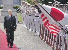  ?? Eugene Hoshiko Pool Photo ?? PRESIDENT BIDEN reviews an honor guard in Tokyo on Monday. “The trip had very little domestic impact — I would say negligible,” one analyst said.