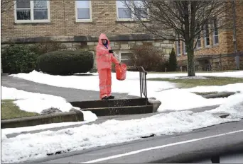  ?? ?? Chris Tetreault, of Tetreault Home and Garden in Central Falls, spreads a salt/sand mixture as ice coats the sidewaolks at Holy Spirit Parish in Central Falls Friday. Rain turned to sleet and freezing rain Friday with the return of colder temperatur­es.