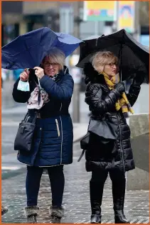  ?? ?? Left, two women struggle with their umbrellas in Sauchiehal­l Street, Glasgow as storms battered the country