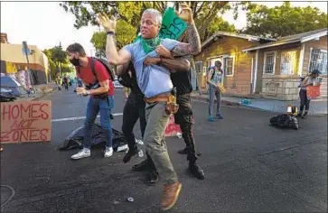  ?? Irfan Khan Los Angeles Times ?? DEMONSTRAT­ORS RESTRAIN a man after he scuffled with other protesters blocking McCadden Place in Hollywood to resist a scheduled city cleanup that would have required homeless people to remove their tents.
