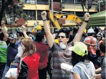  ?? PHOTO: REUTERS ?? People motion to others to be quiet so they can listen for survivors as rescue workers searching under the rubble of a collapsed building after an earthquake hit Mexico Cit.